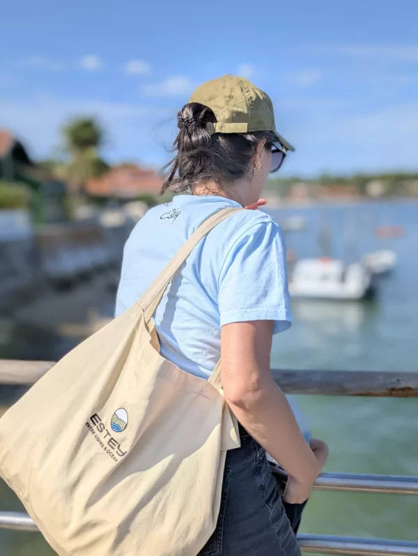 Femme de dos avec le grand cabas de plage brodé « L’Anse » ESTEY, au bord du Bassin d’Arcachon
