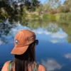 Casquette Le Cap Estey camel portée de dos au bord de l’eau Casquette Le Cap Estey en velours côtelé camel portée de dos au bord d’un plan d’eau