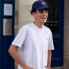 Casquette Le Cap Estey velours côtelé bleu marine portée en ville Homme portant la casquette Le Cap Estey en velours côtelé bleu marine avec un t-shirt blanc, devant une porte ancienne