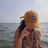Casquette Le Cap Estey velours côtelé camel portée en mer Femme portant la casquette Le Cap Estey en velours côtelé camel à bord d’un bateau, face à la mer