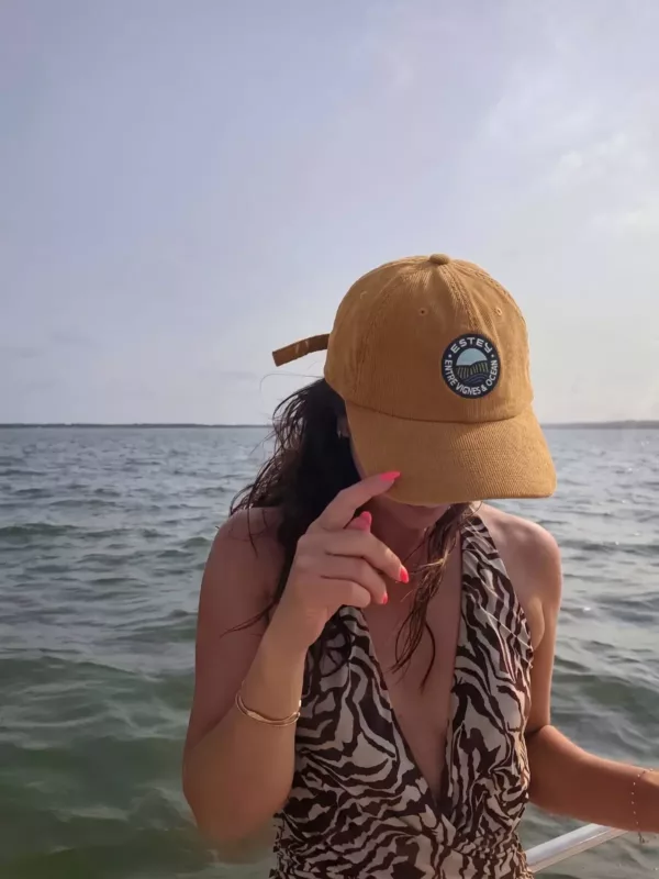 Casquette Le Cap Estey velours côtelé camel portée en mer Femme portant la casquette Le Cap Estey en velours côtelé camel à bord d’un bateau, face à la mer